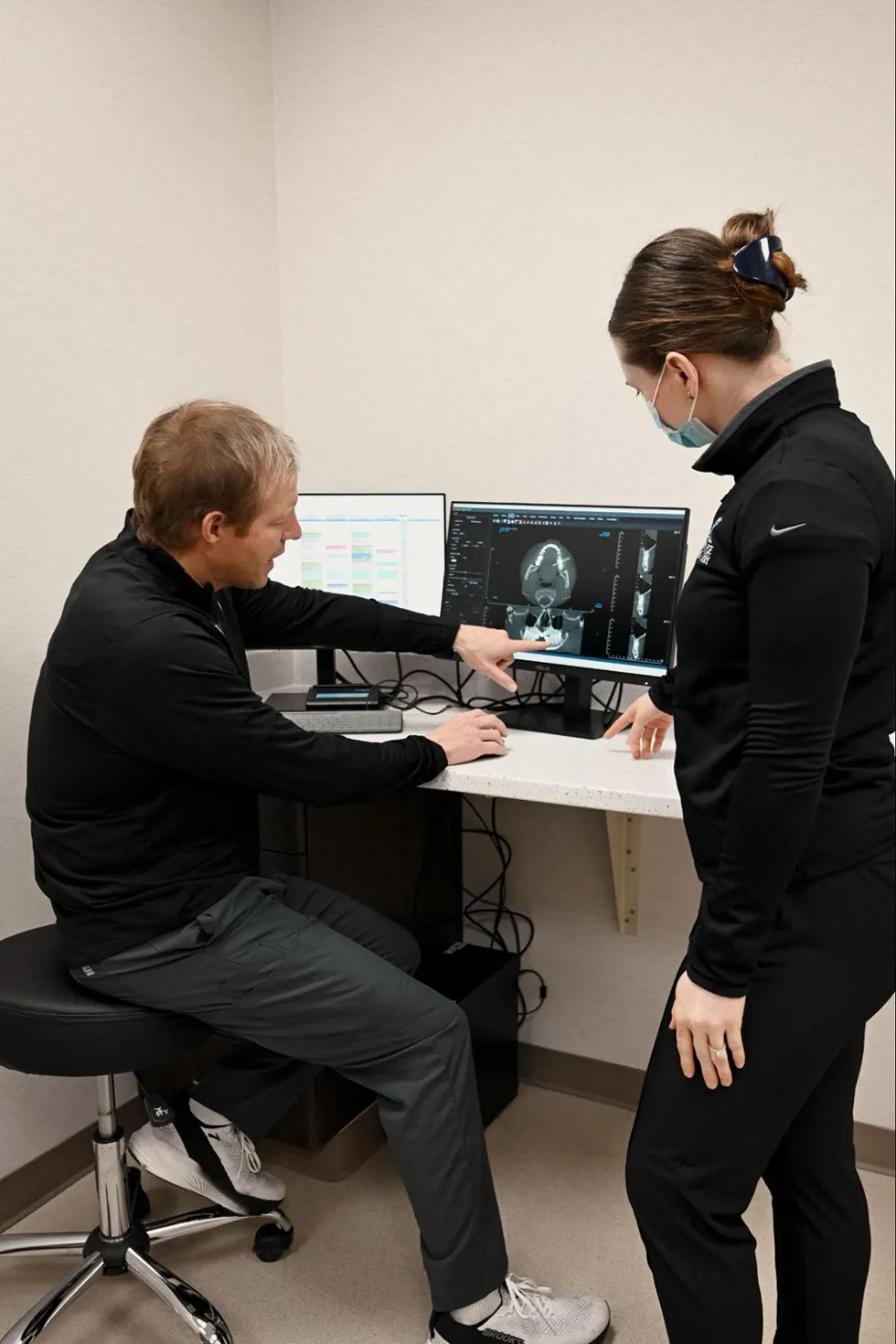 A professional oral and maxillofacial surgeon and a team member at River Ridge Oral Surgery reviewing a 3D CT scan to plan a precise dental implant surgery or impacted tooth extraction.