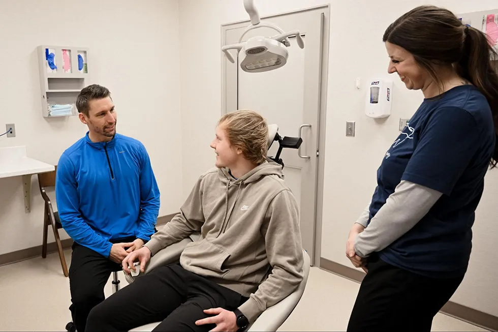 A young patient at River Ridge Oral & Maxillofacial Surgical Center discussing the benefits of removing wisdom teeth with his oral surgeon during a friendly and relaxed surgical consultation.