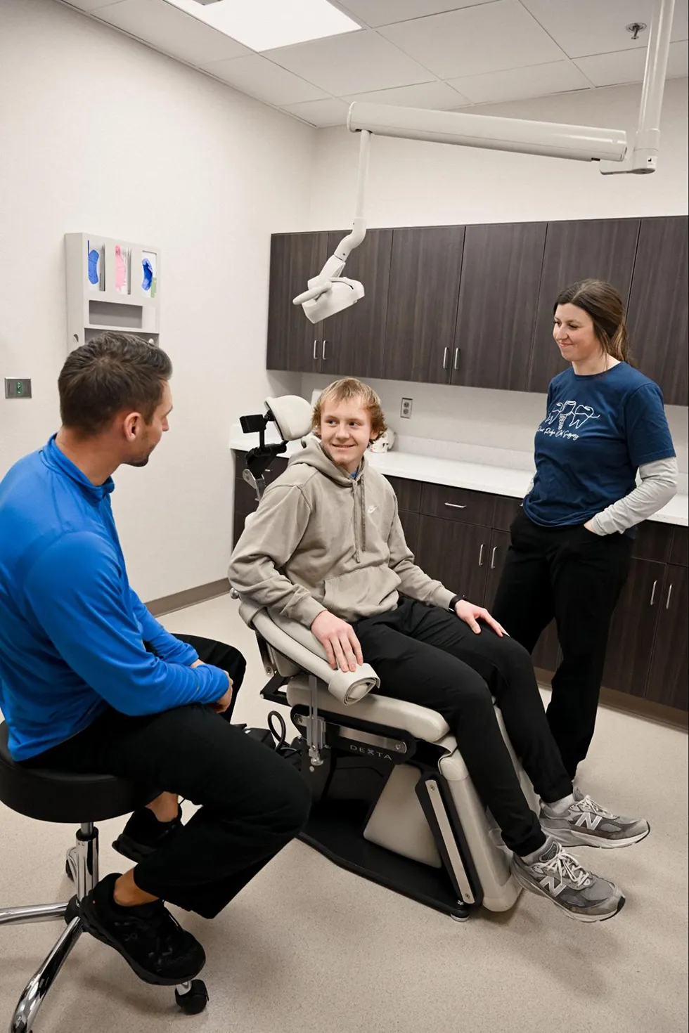 A relaxed young patient at River Ridge Oral & Maxillofacial Surgical Center discussing his treatment plan with an oral surgeon during a modern exam room consultation for wisdom teeth removal surgery.