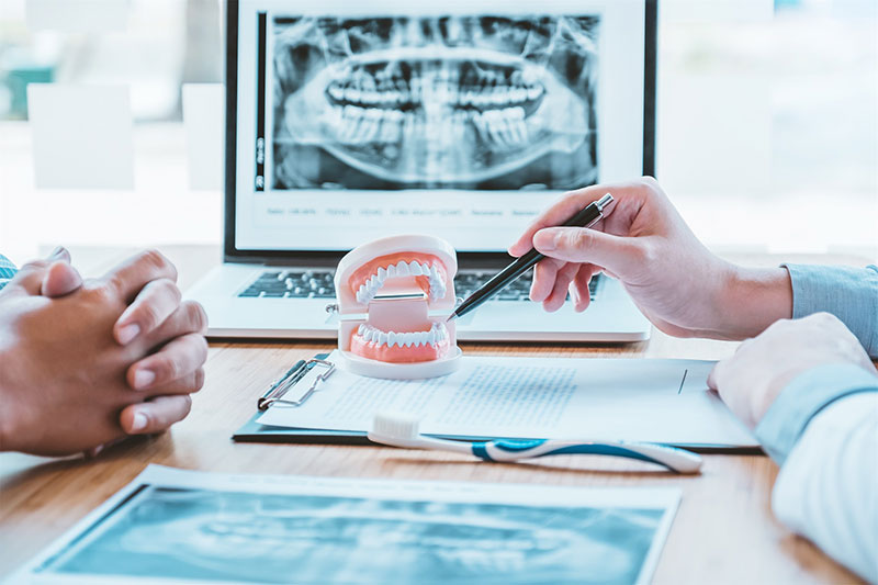 An oral and maxillofacial surgeon at River Ridge Oral Surgery providing a detailed consultation, using 3D X-rays and dental models to explain the process of dental implant surgery and long-term oral health goals.